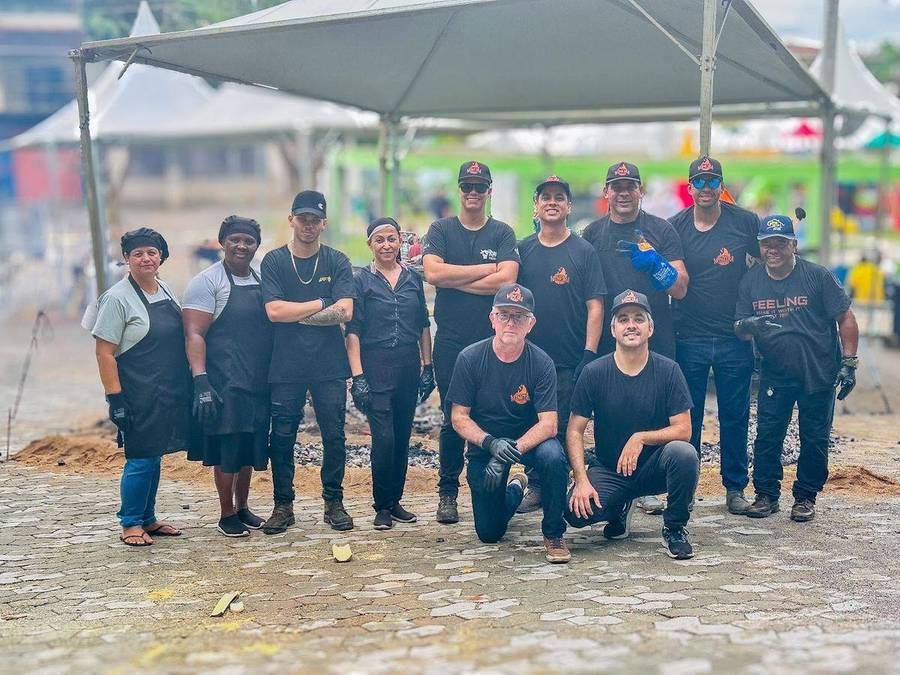 Equipe da Defumaria Mineira uniformizada, sob a tenda, em evento na praça
